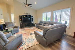Living area with wood finished floors, ceiling fan, recessed lighting, and high vaulted ceiling