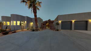 Pueblo revival-style home with driveway, an attached garage, and stucco siding