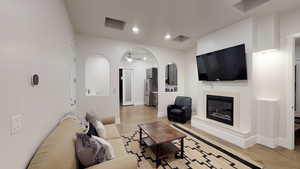 Living room with concrete floors, a glass covered fireplace, and recessed lighting