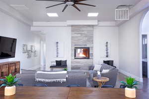 Living area with ceiling fan, a fireplace, and arched walkways