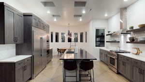 Kitchen with premium appliances, open shelves, light countertops, backsplash, and recessed lighting