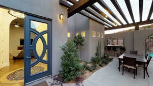 Doorway to property with stucco siding, outdoor dining space, a pergola, and a patio