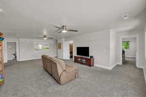 Carpeted living area with plenty of natural light and ceiling fan