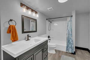 Full bath with vanity, wood finished floors, and shower / tub combo with curtain