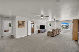 Carpeted living area featuring baseboards and a ceiling fan