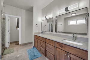 Full bathroom with double vanity and baseboards