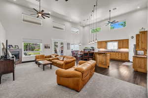 Living room featuring a ceiling fan, a high ceiling, recessed lighting, a tiled fireplace, and plenty of natural light