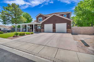 View of front of home featuring a porch, stone siding, a garage, concrete driveway, and stucco siding