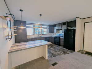 Kitchen with black appliances, wood counters, decorative backsplash, open shelves, and decorative light fixtures