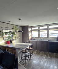 Kitchen featuring dark wood finished floors, a kitchen breakfast bar, and decorative light fixtures