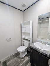 Full bathroom with wood finished floors, vanity, ornamental molding, and a shower