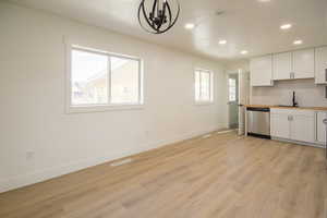 Kitchen with dishwasher, recessed lighting, light wood-type flooring, white cabinets, and a chandelier