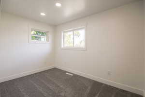 Empty room with dark colored carpet and recessed lighting