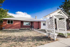 View of front facade with brick siding, a pergola, a chimney, and a front lawn