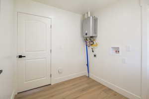 Laundry area with electric dryer hookup, light wood-type flooring, hookup for a washing machine, tankless water heater, and gas dryer hookup