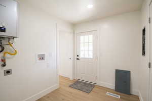 Washroom featuring electric dryer hookup, hookup for a washing machine, light wood-style flooring, and water heater