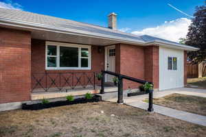 View of front of house with a chimney, brick siding, and a porch