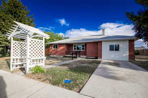 Ranch-style house with a chimney, concrete driveway, board and batten siding, and brick siding