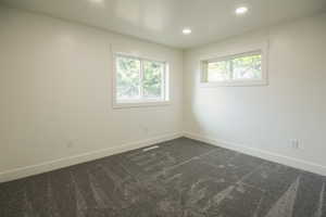 Empty room featuring dark carpet and recessed lighting