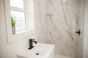 Bathroom with vanity, healthy amount of natural light, and tiled shower