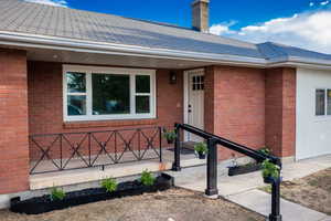 Entrance to property with brick siding and roof with shingles