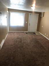 Back House entry door and living room Carpeted foyer featuring a textured ceiling