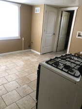 Kitchen with white range with gas stovetop and light tile patterned floors