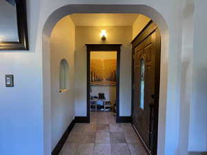 Tiled foyer entrance featuring a textured wall and arched walkways
