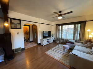Living area featuring arched walkways, ceiling fan, and wood finished floors