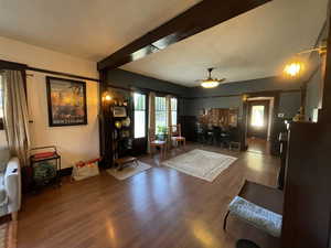Living room with wood finished floors, ceiling fan, and a wood stove