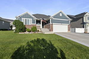 View of front of property with board and batten siding, brick siding, driveway, and a gate