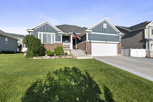 View of front of house with board and batten siding, concrete driveway, brick siding, and a gate