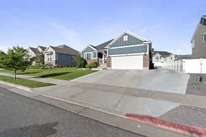 View of front of house featuring board and batten siding, brick siding, a residential view, concrete driveway, and an attached garage