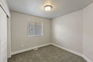Unfurnished bedroom with a closet, dark colored carpet, and a textured ceiling