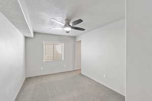 Carpeted spare room featuring a ceiling fan and a textured ceiling