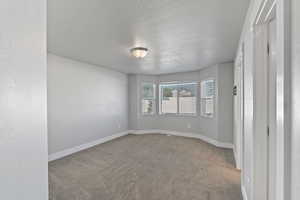 Unfurnished room featuring carpet and a textured ceiling