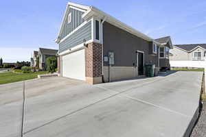 View of side of home featuring board and batten siding, driveway, a residential view, and a garage