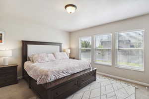 Bedroom featuring light carpet and baseboards