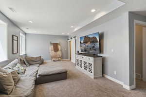 Living area with carpet flooring, a barn door, a textured ceiling, and recessed lighting