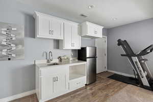Kitchen with freestanding refrigerator, white cabinetry, light wood-style floors, light countertops, and recessed lighting