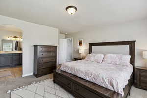 Bedroom with light carpet, arched walkways, and ensuite bath