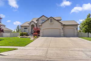 View of front of house with a garage, stucco siding, concrete driveway, stone siding, and a shingled roof