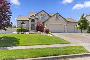 Traditional home with stone siding, a garage, stucco siding, and concrete driveway