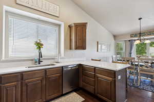 Kitchen featuring dishwasher, lofted ceiling, dark wood finished floors, a peninsula, and light countertops