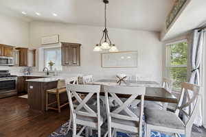 Dining room with plenty of natural light, dark wood finished floors, high vaulted ceiling, and a chandelier