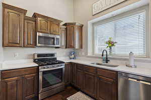 Kitchen with stainless steel appliances, light countertops, and dark wood-type flooring