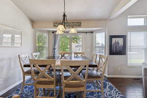 Dining space with healthy amount of natural light, dark wood finished floors, and a chandelier