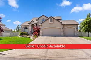 View of front of property with stone siding, stucco siding, concrete driveway, a gate, and a garage