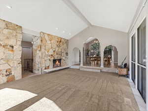 Unfurnished living room featuring arched walkways, carpet, and a fireplace