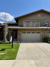 Multi unit property featuring an attached garage, driveway, and a front yard